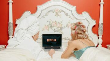 Twee vrouwen die op bed liggen en Netflix kijken.