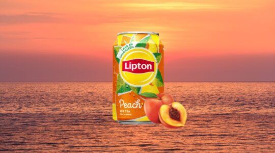 Een blikje Lipton Ice Tea Peach met een zomerse achtergrond.